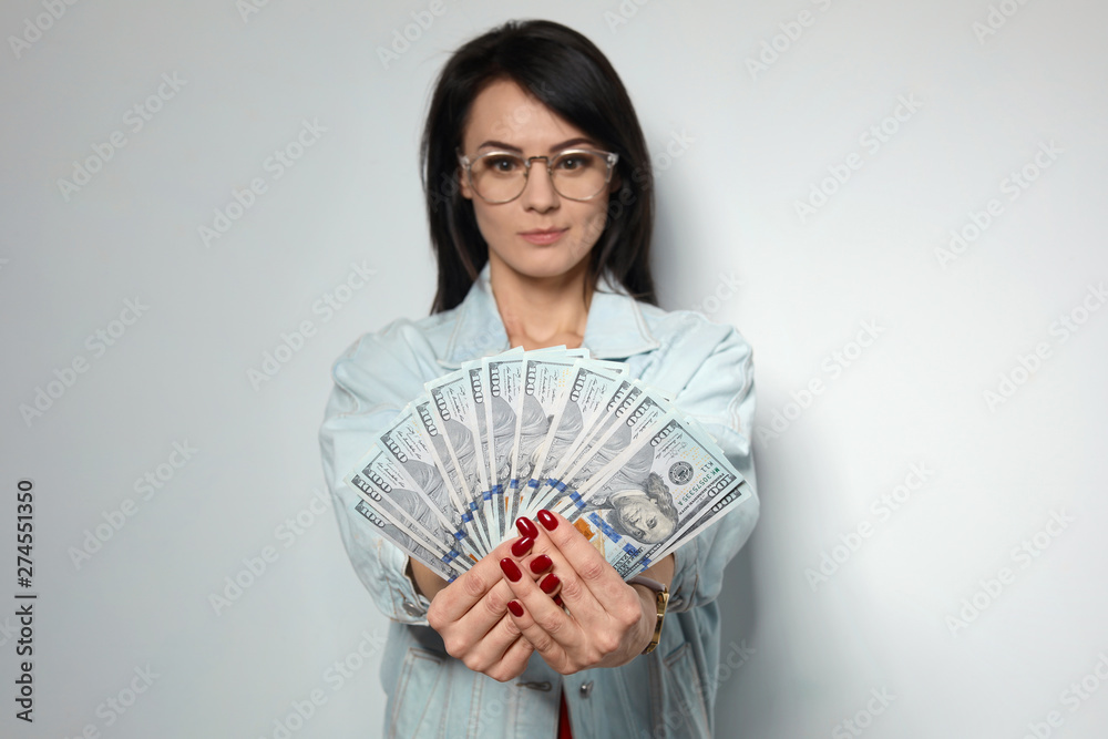 Portrait of stylish woman with money fan on light background Portrait of stylish woman with money fan on light background