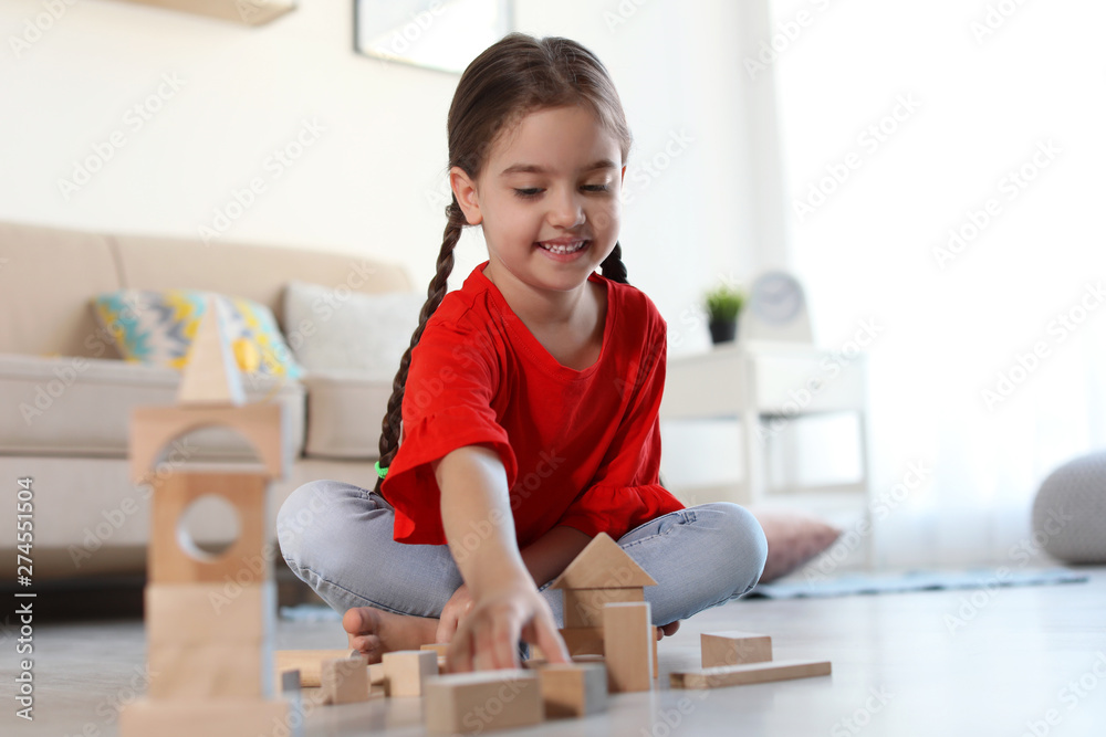 Cute little child playing with wooden building blocks on floor indoors Cute little child playing with wooden building blocks on floor indoors