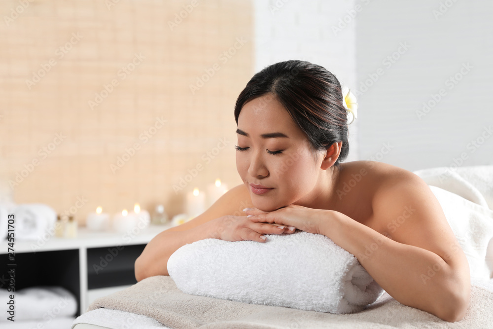 Beautiful Asian woman lying on massage table in spa salon. Space for text Beautiful Asian woman lying on massage table in spa salon. Space for text