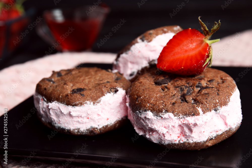 Sweet delicious ice cream cookie sandwiches with strawberry on plate, closeup Sweet delicious ice cream cookie sandwiches with strawberry on plate, closeup