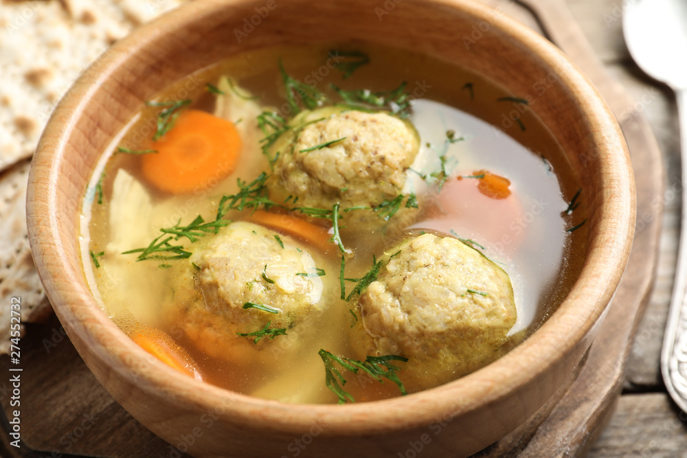 Bowl of Jewish matzoh balls soup on wooden table, closeup