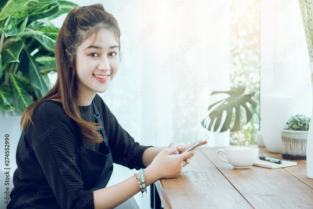 Portrait of young beautiful woman using smartphone to working or shopping online in cafe with cup of coffee on wooden table Portrait of young beautiful woman using smartphone to working or shopping online in cafe with cup of coffee on wooden table