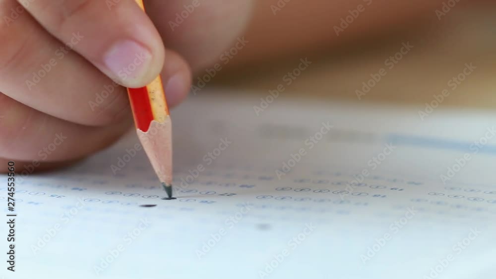 Student hand testing doing test exam with pencil drawing selected choices on answer sheet in school final exams at college or university. Taking multiple choice for assessment in examination classroom Student hand testing doing test exam with pencil drawing selected choices on answer sheet in school final exams at college or university. Taking multiple choice for assessment in examination classroom