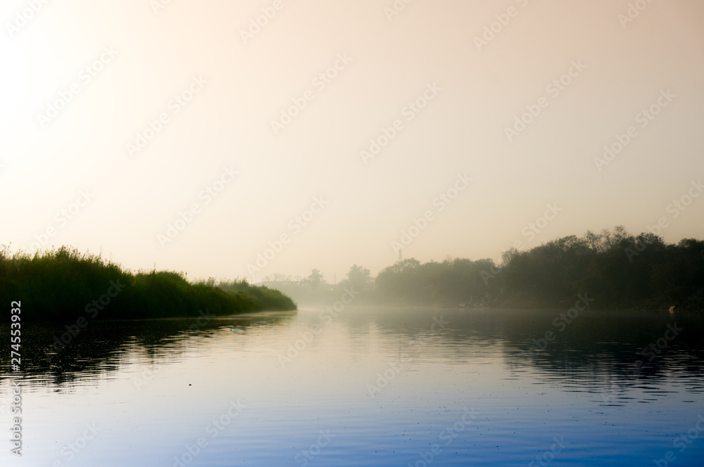 Early morning at yamuna ghat with golden sun, fog and blue water Early morning at yamuna ghat with golden sun, fog and blue water