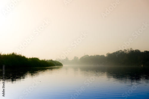 Early morning at yamuna ghat with golden sun, fog and blue water photo