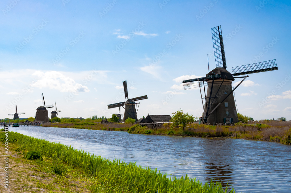 Rural lanscape with windmills close to the river above the blue sky and pretty clouds
