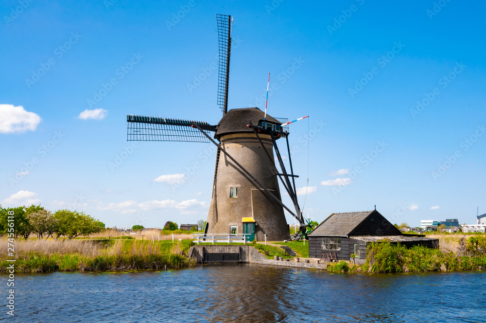 Rural lanscape with windmills close to the river above the blue sky