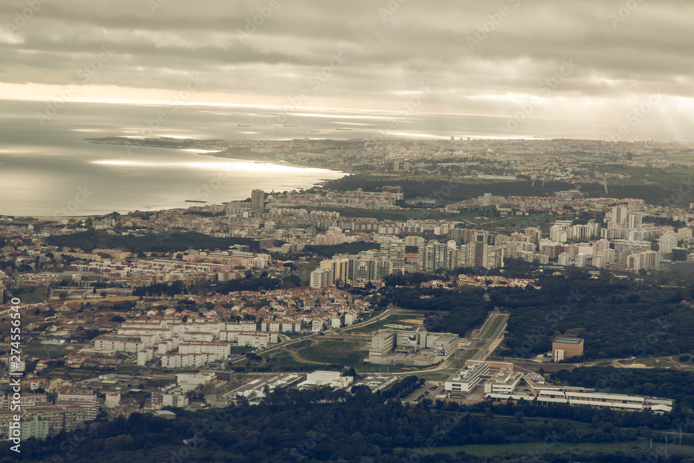 Portuguese capital Lisbon from above. City skyline with clouds in the sky. Buildings and mouth of the river name Tejo with landscape and ships on the horizon