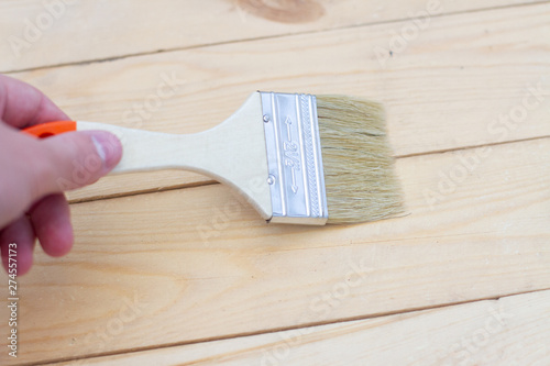paint brush in hand on wooden boards background