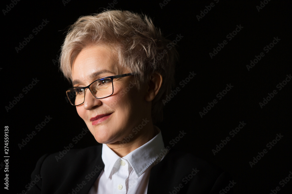 stylish elderly woman in glasses and black jacket on a black background	