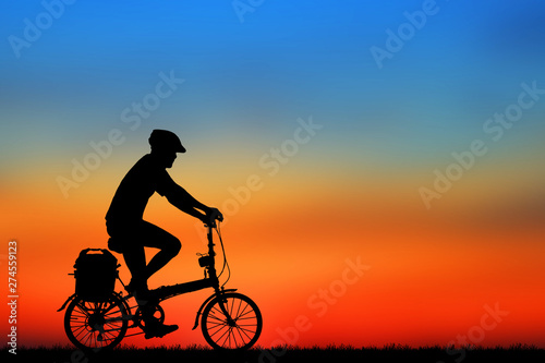 Silhouette man  and bike relaxing on blurry sunrise  sky   background. © rathchapon