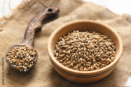 Malt in a wooden bowl on the white kitchen table background.
