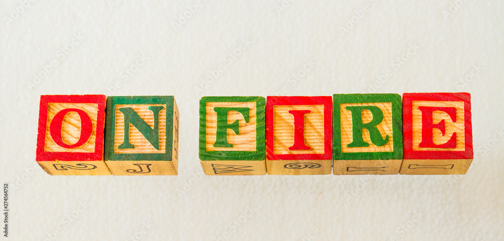 The term on fire visually displayed on a clear background using colorful wooden blocks image in landscape format with copy space