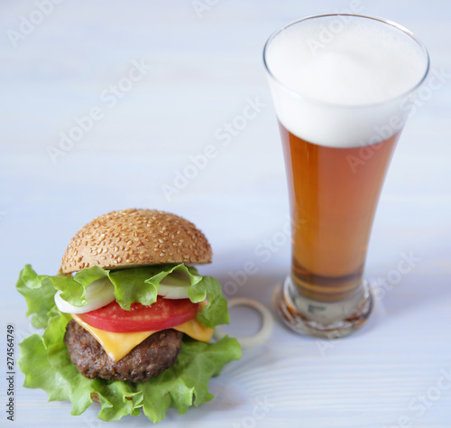 hamburger with a glass of beer on a wooden white background with copy space for text.