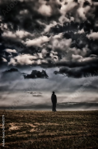Man in black clothes standing on horizon under datk cloud © Jansk