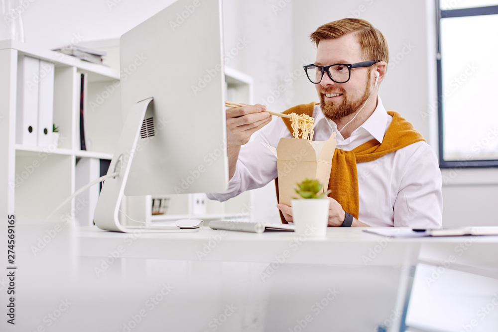 Mid age businessman having lunch at the computer in the office Mid age businessman having lunch at the computer in the office