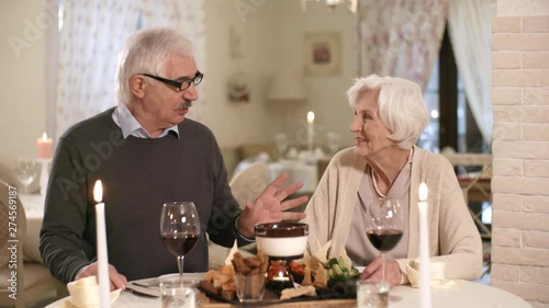 Wallpaper Mural Waist-up shot of 60-something senior Caucasian gentleman dining with his wife in candlelit restaurant, telling her something and gesturing animatedly while she is listening and offering her opinion Torontodigital.ca