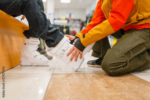 Man helps woman to trying on ski boots, shopping photo