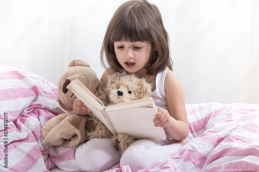 Cute little girl smiling while lying in a cozy white bed Cute little girl smiling while lying in a cozy white bed