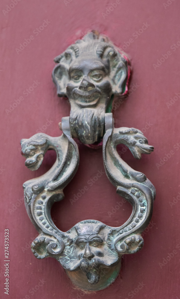 An old style decorative bronze door handle on a wooden door, the distinctive feature and symbol of Malta in Mdina.