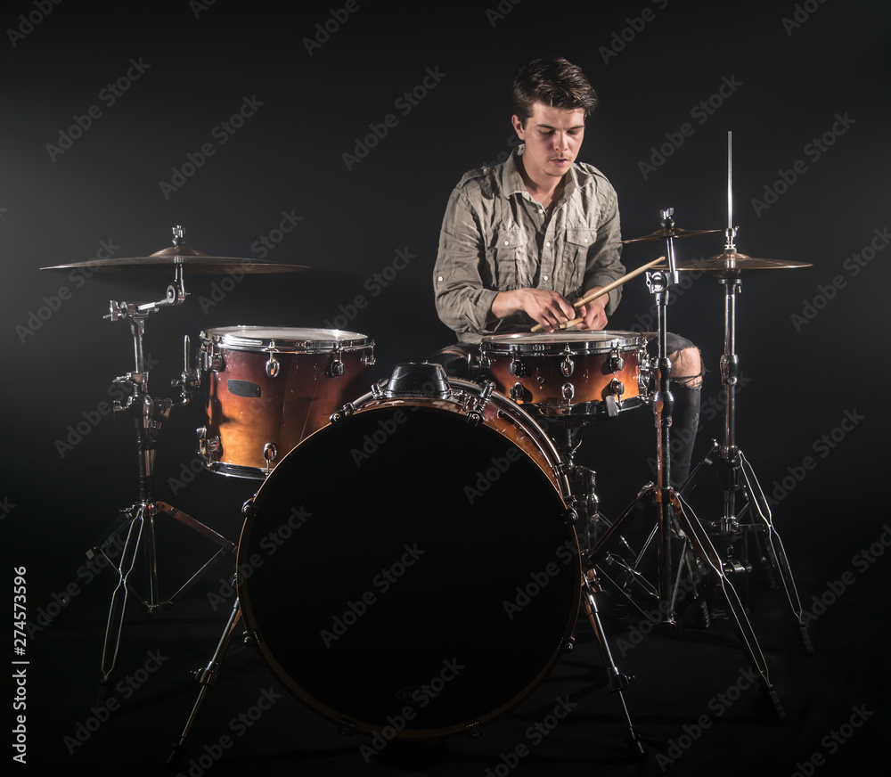 Fototapeta premium Professional drummer playing on drum set on stage on the black background