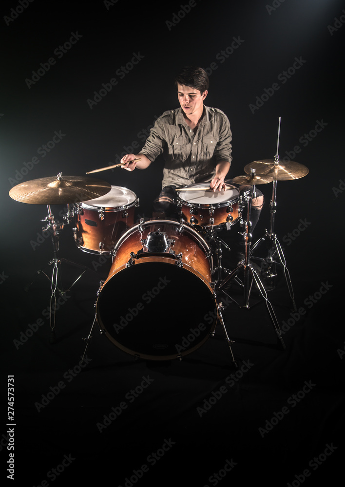 Fototapeta premium Professional drummer playing on drum set on stage on the black background