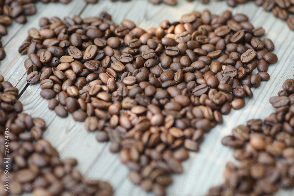 Fototapeta premium Coffe beans in hands and on the wooden table, roasted arabica