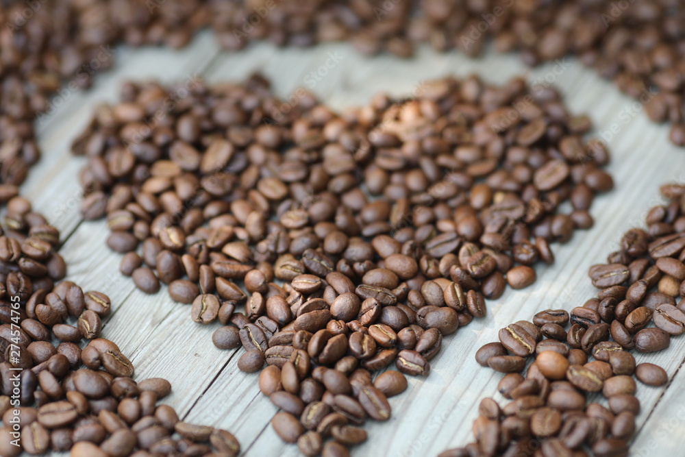 Fototapeta premium Coffe beans in hands and on the wooden table, roasted arabica