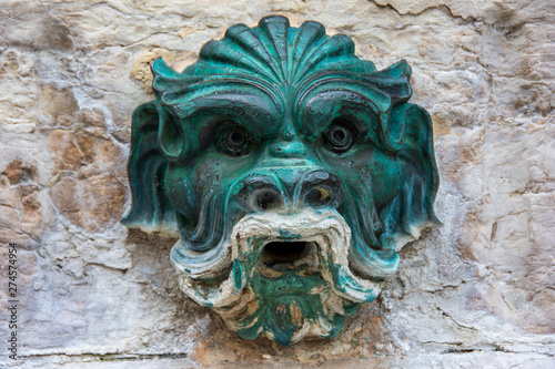 Canvastavla Tête de gargouille ancienne en bronze sur un mur de vieille pierre, sculpture de