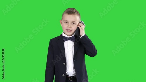 Little boy in a costume making a phone call while walking on a Green Screen, Chroma Key. photo