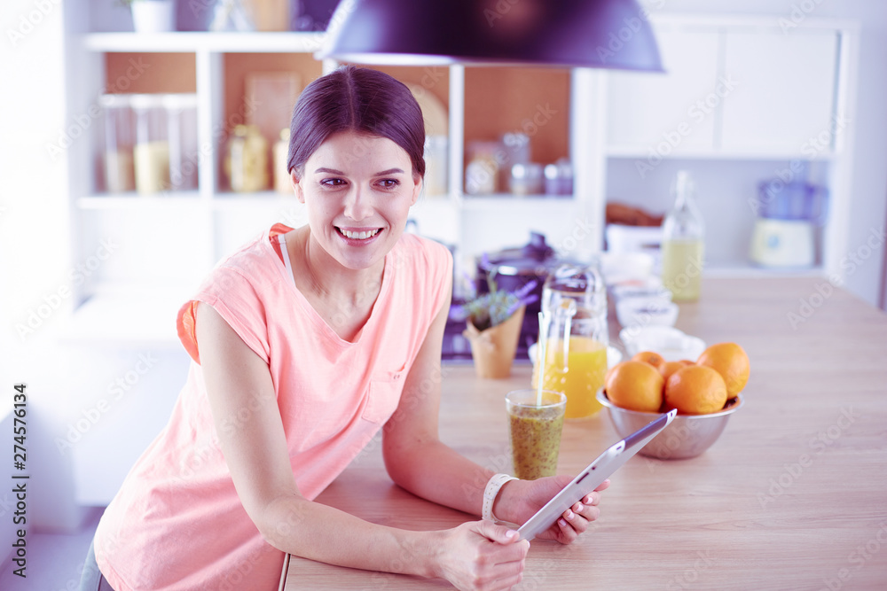 Beautiful young woman using a digital tablet in the kitchen Beautiful young woman using a digital tablet in the kitchen