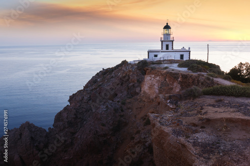 Cliffs and lighthouse in Akrotiri at sunset, Santorini, Greece.  © happyimages