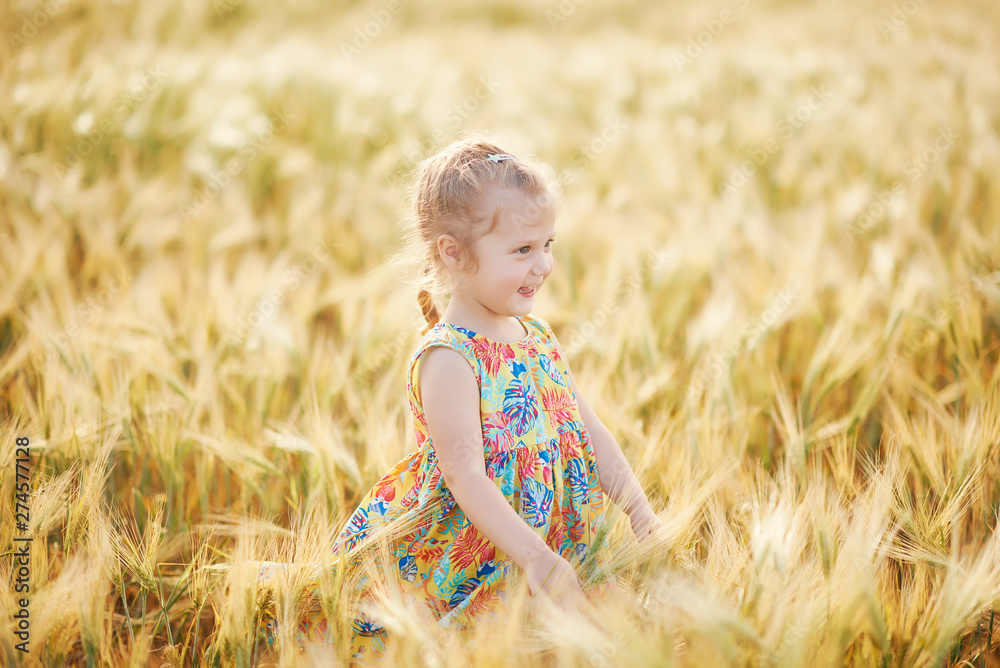 Cute child walking in the wheat golden field on a sunny summer day. Girl smiling and happy. Nature in the country Cute child walking in the wheat golden field on a sunny summer day. Girl smiling and happy. Nature in the country