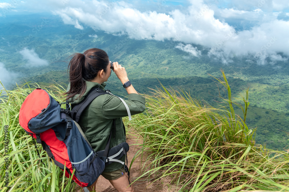 Hiker asia woman look binoculars and standing on mountain. Female adventure backpack and camping on hike in outdoor nature. Travel Concept Hiker asia woman look binoculars and standing on mountain. Female adventure backpack and camping on hike in outdoor nature. Travel Concept