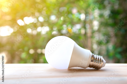 LED bulb on the wooden table and lighting of sub lay with green nature background for eco saving concept