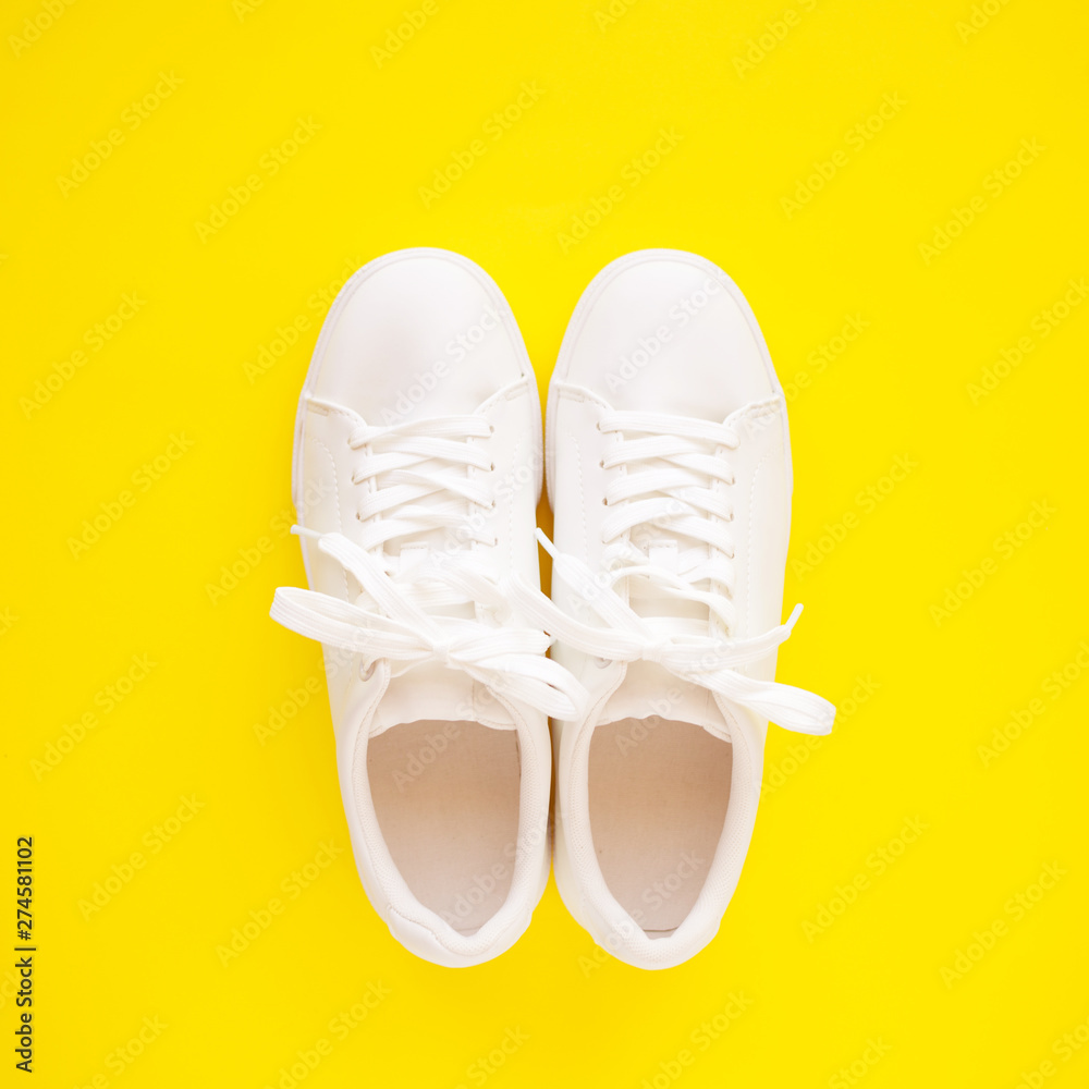 Perfect white New sneakers standing on a bright yellow background. Perfect white New sneakers standing on a bright yellow background.