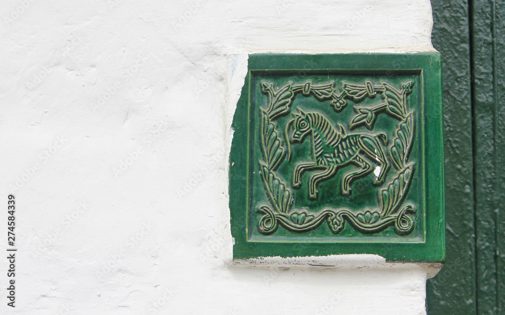 Decorative tile ornament on old house wall 