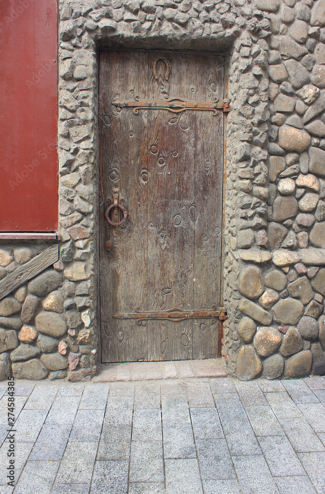 Old wooden door at medieval house facade. Retro style architecture with stone archway at aged building front Old wooden door at medieval house facade. Retro style architecture with stone archway at aged building front