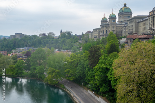 The parliament of Bern, The Bundeshaus, with lush trees and aare river on cloudy sky background