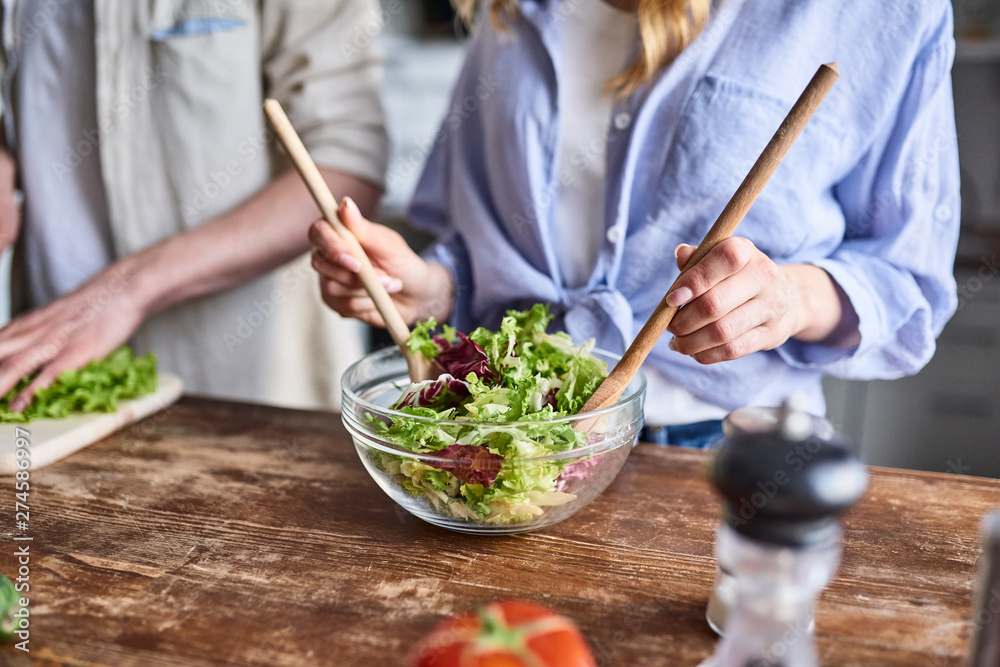 Couple preparing salad in kitchen