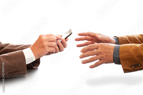 Hands from two businessmen in conversation by a desk. One texting on a cell phone. Negotiating business or a job interview. - Image