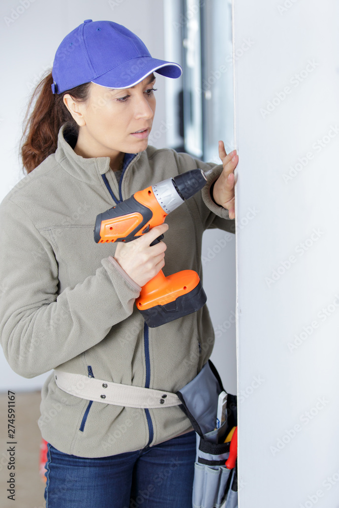 woman in construction helmet with a drill in hand woman in construction helmet with a drill in hand