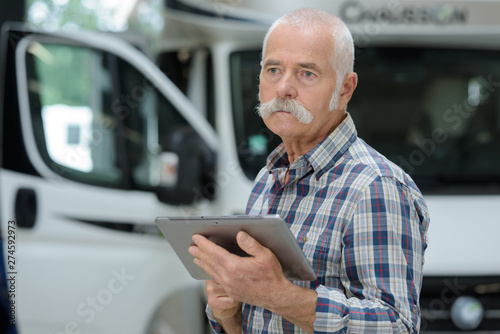 senior logistics man next to container truck with tablet