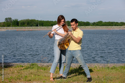 The guy playing the horn and the girl playing the flute on the lake © biggur