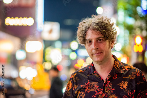 Photography Portrait of a middle aged man traveling and enjoying the nightlife in Tokyo, with beautiful blurry lights behind