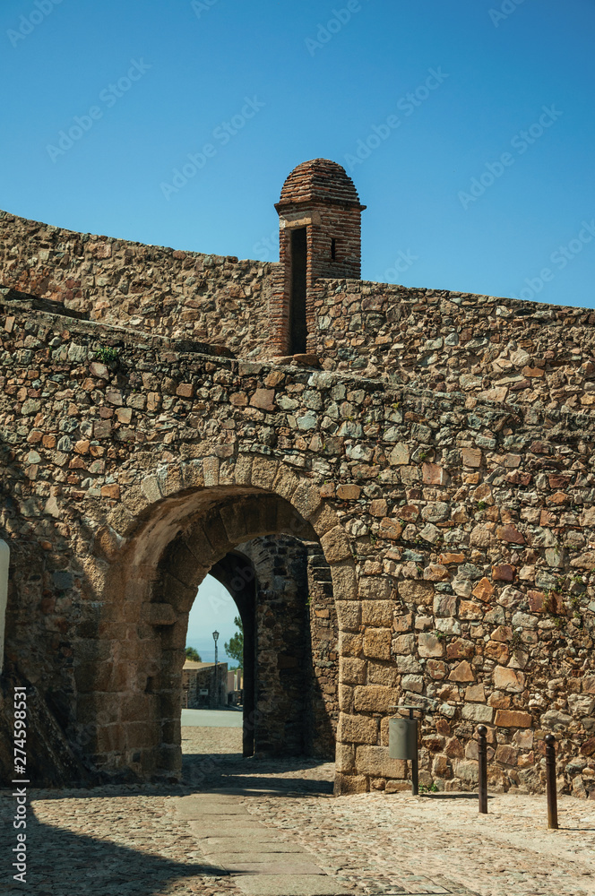 Gateway in wall made of rough stone with watchtower
