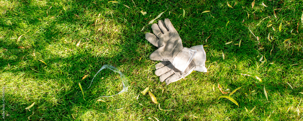 working in garden, protective gloves and glases laying on green grass working in garden, protective gloves and glases laying on green grass