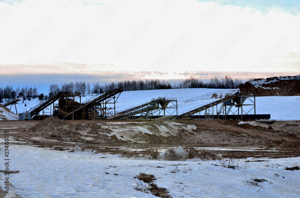 Sand mining in winter conditions in an industrial quarry. Conveyor Belt in mining quarry, Mining industry. Amazing mountains against the backdrop of snow and industry