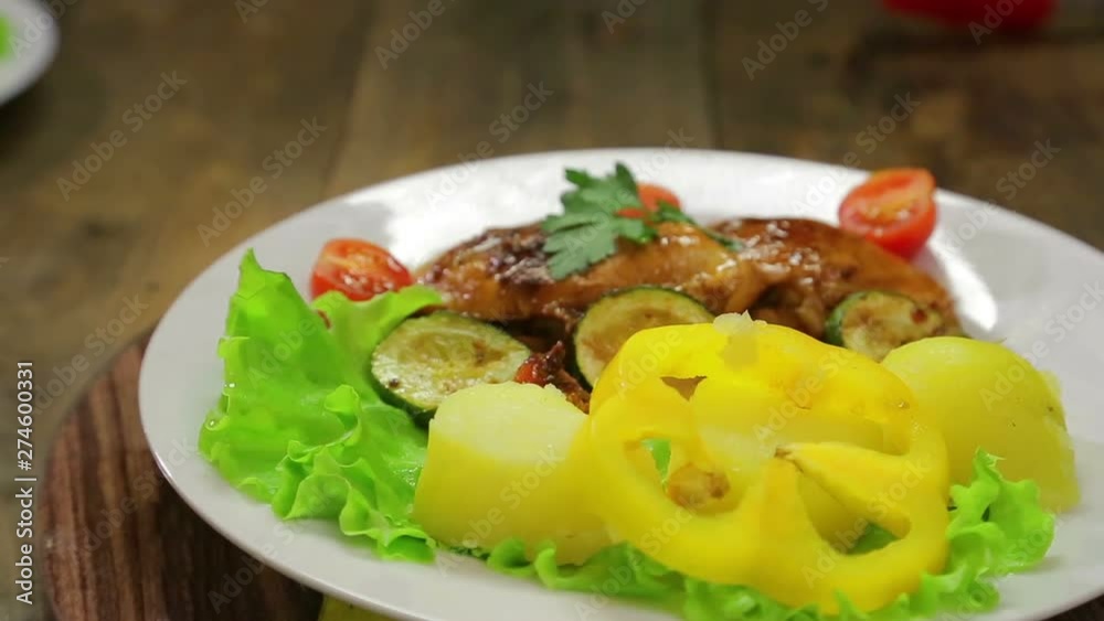 A rotating plate with a grilled chicken dish and a side dish of vegetables. A rotating plate with a grilled chicken dish and a side dish of vegetables.