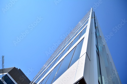 New office building in business center. Wall made of steel and glass with blue sky. 